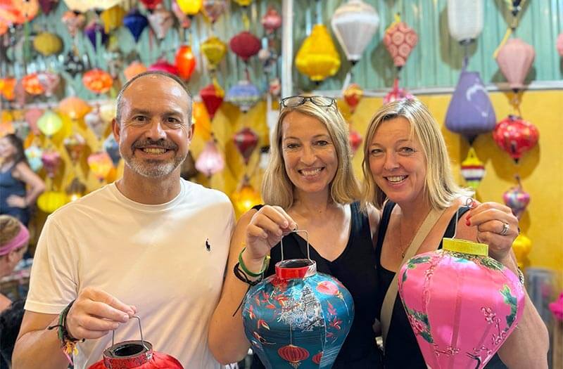 A family on tour with authentic adventures with adam donovan posing for a picture at a vietnam lantern making workshop.