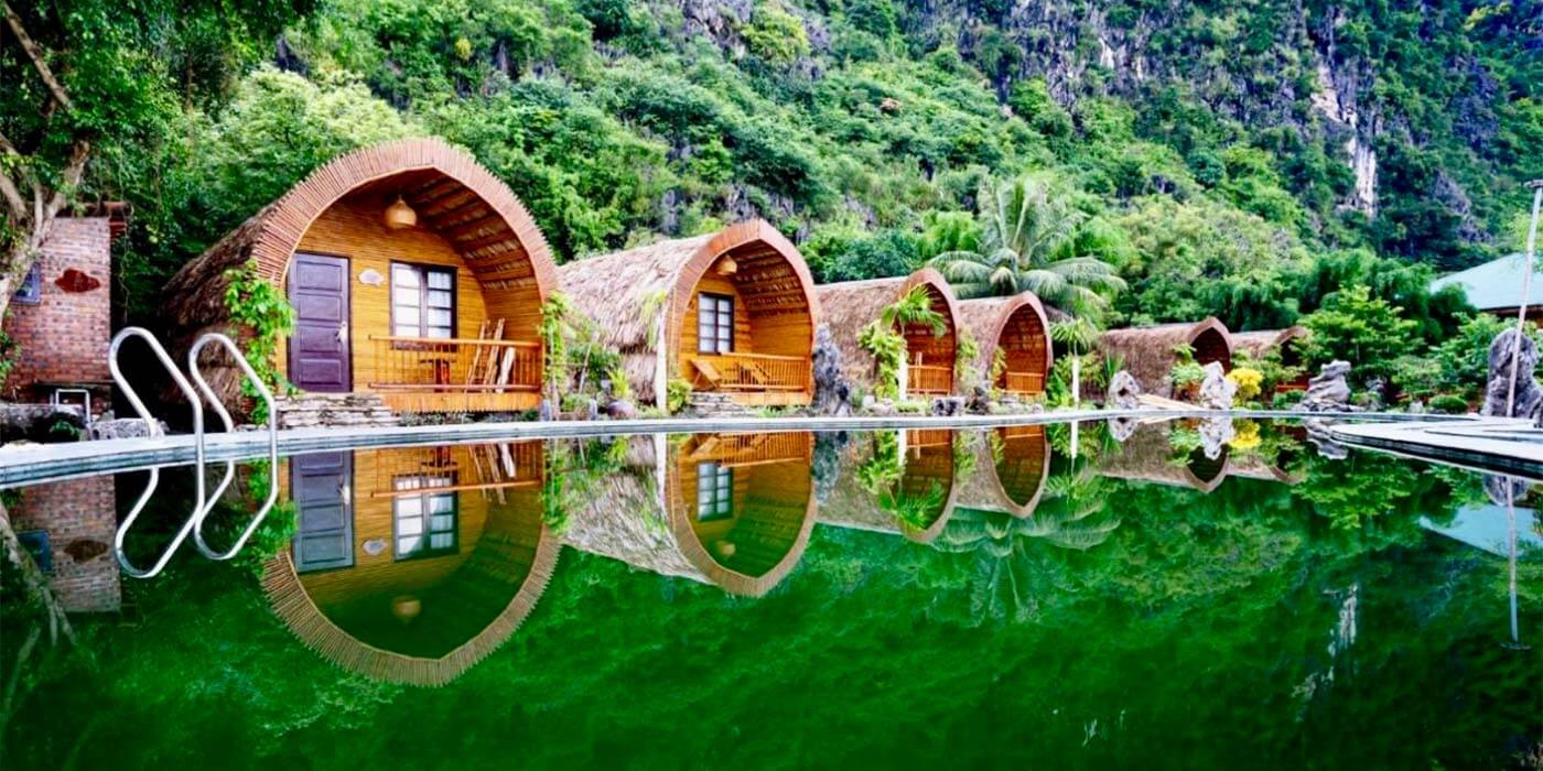 The eco bungalows in Vietnam reflecting in the beautiful clear waters at the base of the mountains.