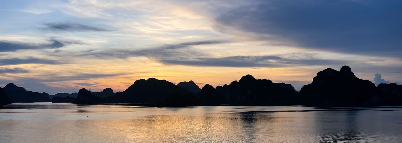 The beautiful sunset in a Vietnamese bay over the water and iconic moutnains.